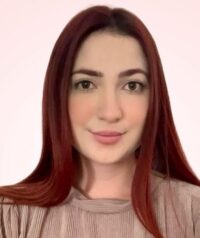 A woman with straight, long reddish-brown hair and fair skin is facing the camera, wearing a light-colored top against a plain background—perfect for an Acerca de nosotros introduction. - Mereces Jeremías Veronica Jaramillo